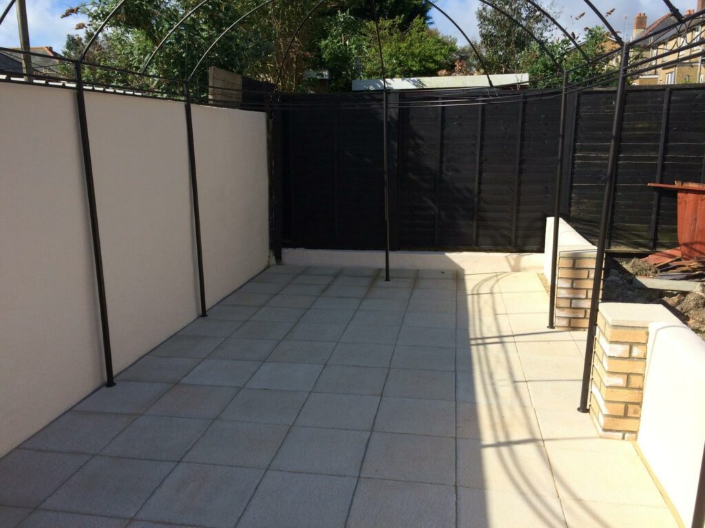 Newly paved patio area with brick steps and black fence